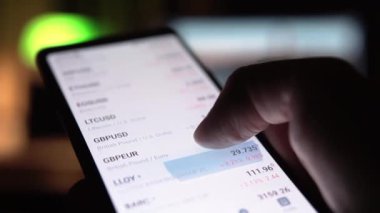 Adam akıllı telefondan hisse senedi grafiklerini ve fiyatlarını izliyor.