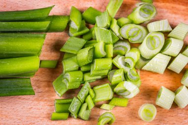 Doğranmış soğan, soğan ya da taze soğan, ahşap tahtaya yakın. Yeşil salata mezesi hazırlığı. Çiğ vejetaryen yemeği. Üst görünüm.