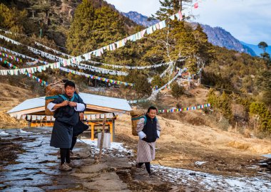 Thimphu / Bhutan - Şubat 2016: Geleneksel erkek kıyafetleri içinde üç Bhutanlı Gho ve geleneksel hasır sırt çantalı Bhutan dağlarındaki Phajoding Manastırı 'nda mal taşımak için.