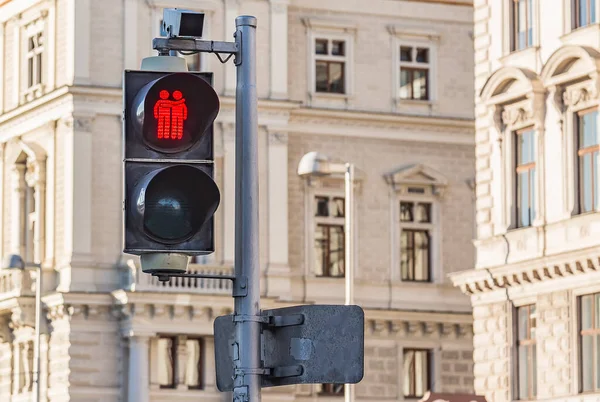 Red forbidding traffic light prohibit for pedestrians to cross the street in european city on background of old classic building. Two red little men hugging