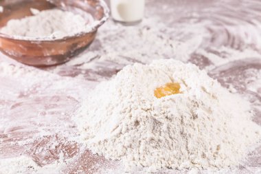 Manzara pişirme, bir kase buğday unu, bir bardak süt ve hamur yoğurmak için bir yığın un, üstünde çiğ yumurta..