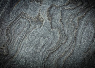 Eş merkezli daireler desenli koyu gri, ham granit arkaplan.