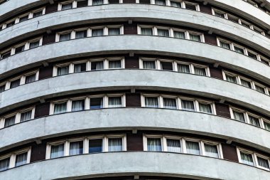 Yüksek silindirik gri bir otel binasının üniforma pencereleri. Şehir arka planı..