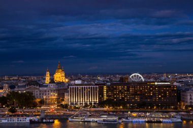 Budapeşte, Macaristan - 10 Ekim 2019: Budapeşte 'nin dönme dolabı Budapeşte Gözü, kıtalararası otel ve Tuna nehri üzerindeki nehir tekneleri ile aydınlatılmış gece panoraması.