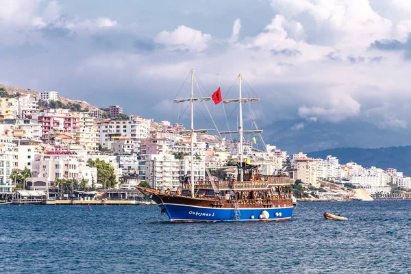 Arnavutluk 'un Saranda kenti - Eylül 2019: Saranda kentinin arka planında Arnavutluk' un Saranda kentinde deniz turları için Onhesmus adlı eski gemi yelkenli direği bulunuyor. Bulutlu bir gün. Deniz manzarası.