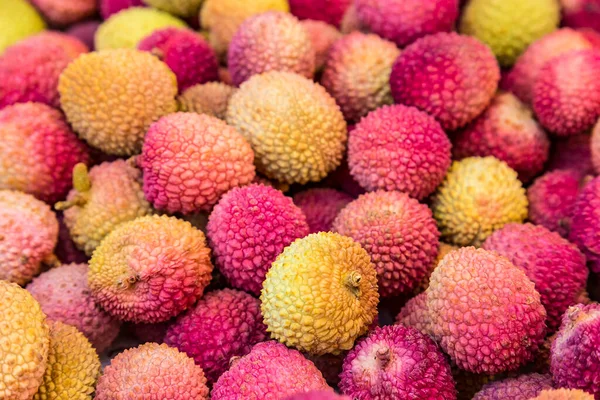 Fresh red and yellow litchi fruits on the market, also known as lichee, lychee, or lichi, Litchi chinensis natural food background.