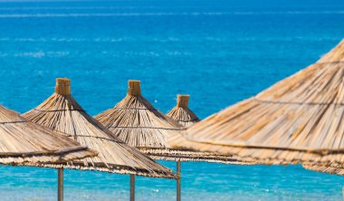 Turkuaz bir arka planda kamış plajı şemsiyelerinin yakın çekimi..