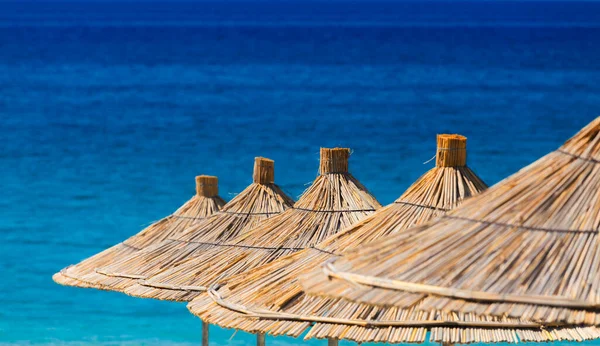 Turkuaz bir arka planda kamış plajı şemsiyelerinin yakın çekimi..