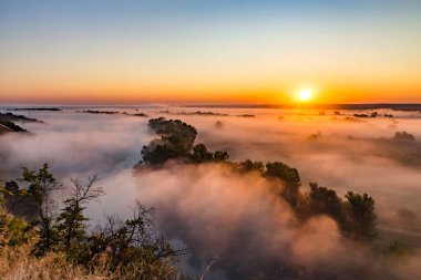 Nehir vadisinin sonbaharda sabah erken saatlerde yoğun sisle kaplı olduğu güzel panoramik manzara. Gün doğumu.