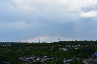 Gökkuşağının önündeki yüksek voltajlı elektrik hatları