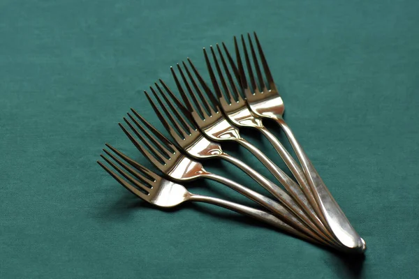 six metal forks on green background