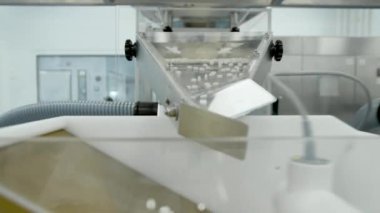 İlaç fabrikasının atölyesinde beyaz haplar metal otomatikler üzerinde hareket ediyor. Eczacılık kimya şirketinde, uyuşturucu kullanımına yakın görünüm, iş süresince taşıyıcı bant boyunca ilerler