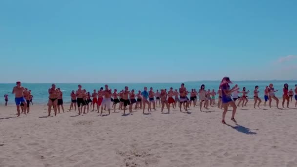 ビーチで踊る若い人たちの大規模なグループの空中ビュー。黒海沿岸。ビーチでのスポーツ活動. — ストック動画