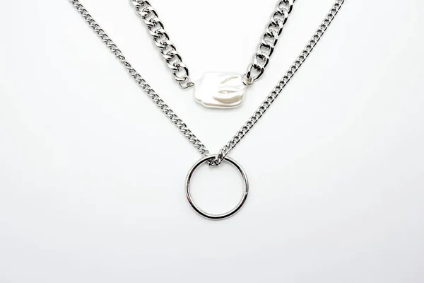 Bijouterie. Dva stříbrné řetězy a krásný lesklý bílý drahokam na bílém pozadí. Koncept šperků Stock Obrázky