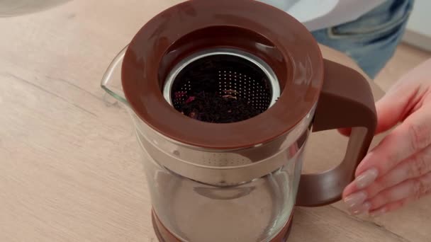 Close up of a woman brewing black tea in the morning. Woman pouring boiling water into a teapot in which black tea with wild berries is brewed — Stock Video