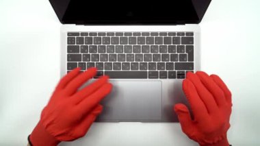 Elma Macbook Pro klavyesine yazı yazan kırmızı koruyucu eldivenli eller, 4K çözünürlükte görüntüyü kapatın. 4K, UHD atışı. Ağ iletişimi, çevrimiçi alışveriş veya laboratuvar işi kavramı