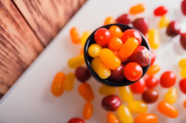 Beyaz ve ahşap arka planda çeşitli renkli domatesler. Yaratıcı tasarım, güzel ışıklandırma.