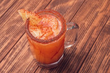 Michelada birası ve domates suyu. Tahta masada biralı Clamato. Meksika içkisi. Meksika yemeği.