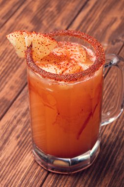 Michelada birası ve domates suyu. Tahta masada biralı Clamato. Meksika içkisi. Meksika yemeği.