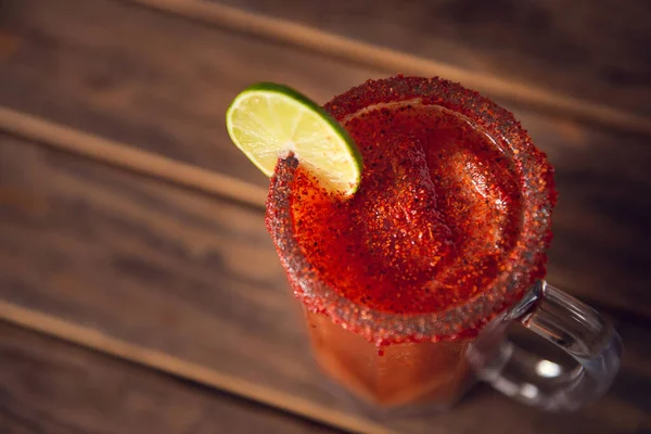 Michelada birası ve domates suyu. Tahta masada biralı Clamato. Meksika içkisi. Meksika yemeği.
