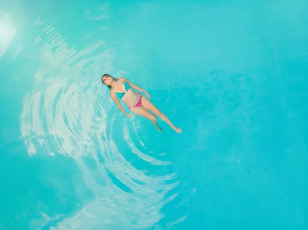 在清澈的蓝绿色的大海中 一个悠闲的年轻女子的空中形象 在酒店游泳池休息的苗条女人的头像 — 图库照片