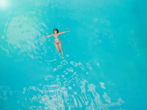在清澈的蓝绿色的大海中 一个悠闲的年轻女子的空中形象 在酒店游泳池休息的苗条女人的头像 — 图库照片