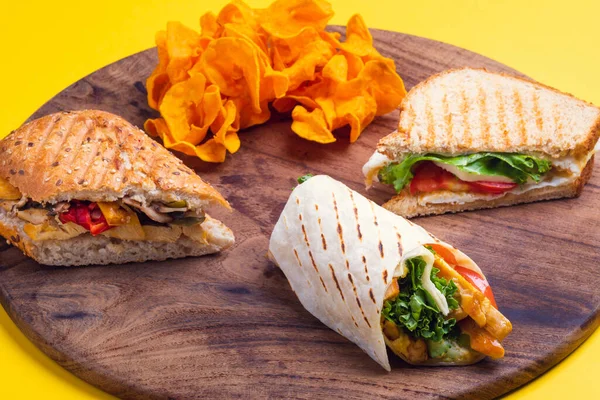 Sağlıklı sandviçler ve ambalajlar ahşap masa ve sarı arka planda atıştırmalıklar.