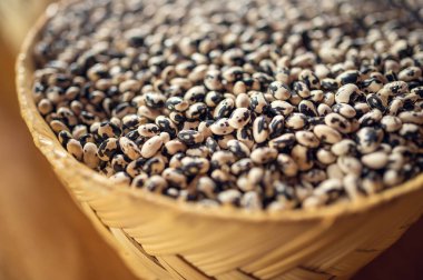 Hasır sepette egzotik renkli Meksika fasulyesi. Baklagillerin en üst görüntüsü. Fasulye yemeği kavramı. Tahta masada egzotik fasulyeler. Fasulyelerin kırsal arka planı. Kırsal ortamda renkli baklagiller.