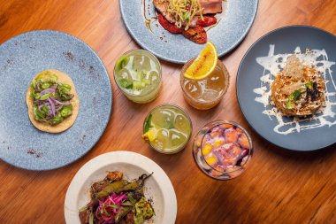 Farklı tabaklar ve ahşap masada alkollü kokteyller olan yemek masası. Restoran konsepti. Gurme tablo ayarları