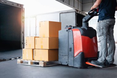 İşçiler paket kutularını konteynır kamyonuna boşaltıyorlar. Forklift Palet Jack. Rıhtım Deposu yükleniyor. Depo Nakliyat, Malzeme Zinciri, Malzeme Sevkiyatı, Nakliye Kamyonu Lojistik, Kargo Taşımacılığı.