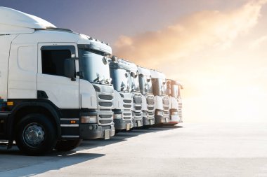 Semi Trucks on The Parking Lot at Sunset Sky. Big Rig. Tractor Truck. Shipping Cargo Container Trucks at The Port. Economy Business Transport on Road. Trucking. Freight Logistics Transport.