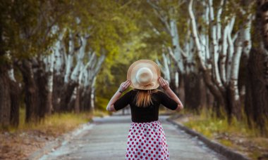 Bir huş ağacının arka planında, yaz şapkalı bir kız..