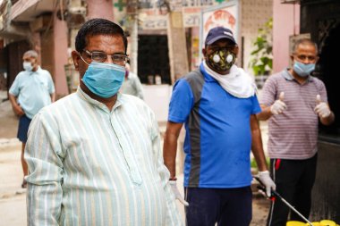 Yeni Delhi, Delhi / Hindistan - 8 Haziran 2020: Korona virüsünden korunmak için bölgelerini temizleyen orta yaşlı insanlar