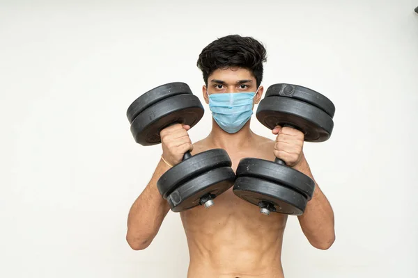 Salgın için maske takan sporcu kol, kol, kol ve omuzlar için egzersiz yapıyor. Salgın zamanında antrenman yapıyor.
