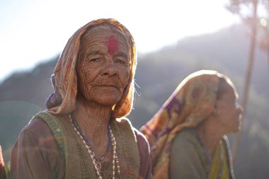 Almora, Uttrakhand / Hindistan - 4 Haziran 2020: Bir orta portre ya da yüzünde birçok kırışıklıklar olan yaşlı bir köylü kadın ormanda oturan pembe bir bluz giyiyor..