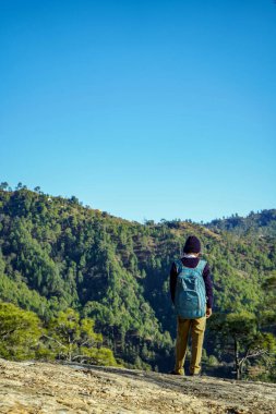 Almora, Uttrakhand / Hindistan - 30 Mayıs 2020: Tepesinde güzel mavi gökyüzü olan bir dağın yamacında duran bir okul çocuğu.