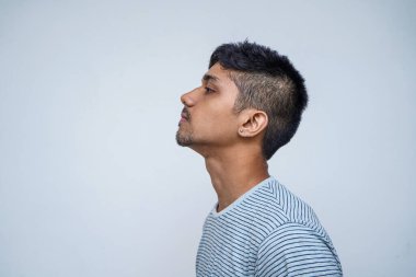 Şehvetli ve düşünceli. Yakışıklı genç Hintli erkek modelin portresi beyaz arka planda dururken şehvetli ve düşünceli oluyor..