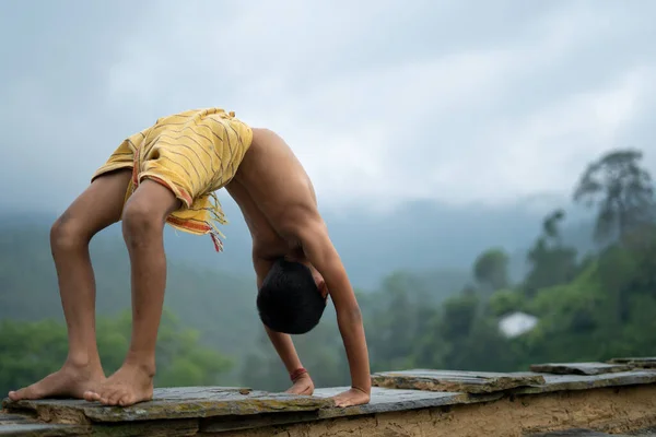 Genç Hintli şirin bir çocuk dağlarda yoga yapıyor, dhoti giyiyor.