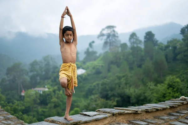 Genç Hintli şirin bir çocuk dağlarda yoga yapıyor, dhoti giyiyor.