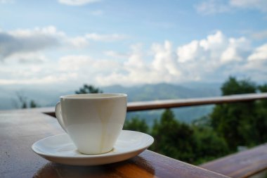 Dağların tepesinde bulutlu bir yerde çay fincanı. Güzellik doğası
