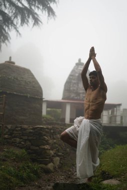 Parçalanmış vücutlu genç adam dhoti giyer, sabahın erken saatlerinde tapınakta dua eder..