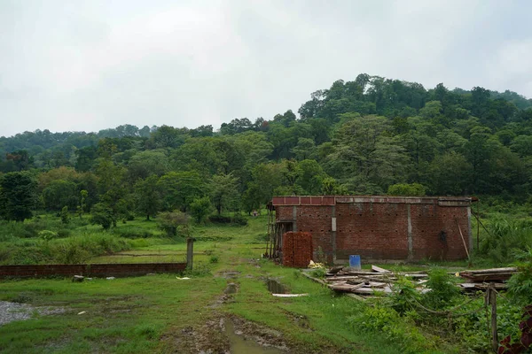 a house being constructed with red bricks in between mountain range.