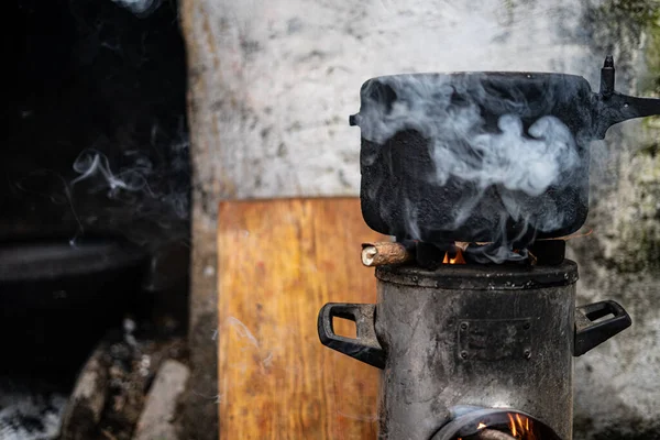 Pressure Cooker kept on top of a modern chulah with wood being burnt.