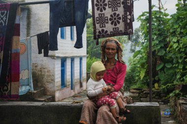 ALMORA, Hindistan - 06 Eylül 2020: Yaşlı bir kadının portresi, sari giymiş ve kucağında bir çocuk tutuyor..