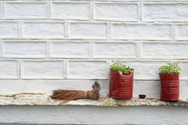 İki kırmızı teneke tencerenin yanında tutulan küçük süpürge..