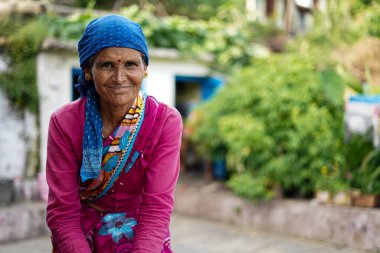 Almora, Uttrakhand / Hindistan - 4 Haziran 2020: Bir orta portre ya da yüzünde birçok kırışıklıklar olan yaşlı bir köylü kadın ormanda oturan pembe bir bluz giyiyor..