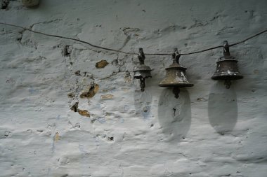Hindistan 'da beyaz bir duvar tapınağında asılı eski tip çanlar.