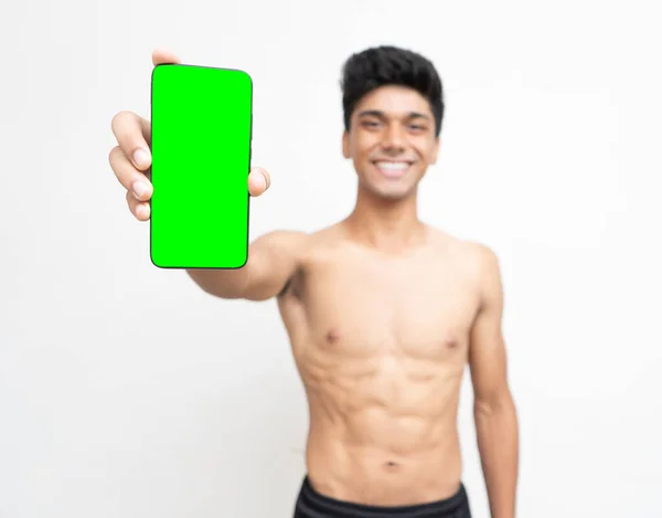 緑の画面の電話を持っている若いインドの少年は 背景に親指を表示します — ストック写真