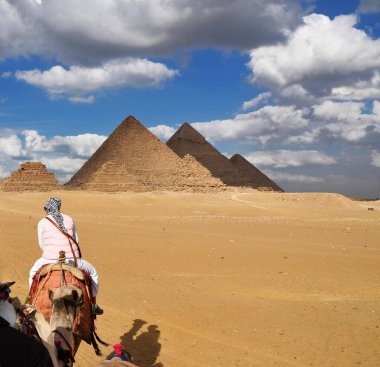 Deveye binmiş bir turist Mısır piramitlerine doğru gidiyor.