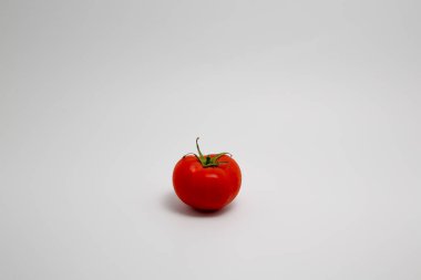 Beyaz zemin üzerinde izole edilmiş kırmızı organik domatesin fotokopi alanı ile yakın plan çekimi.